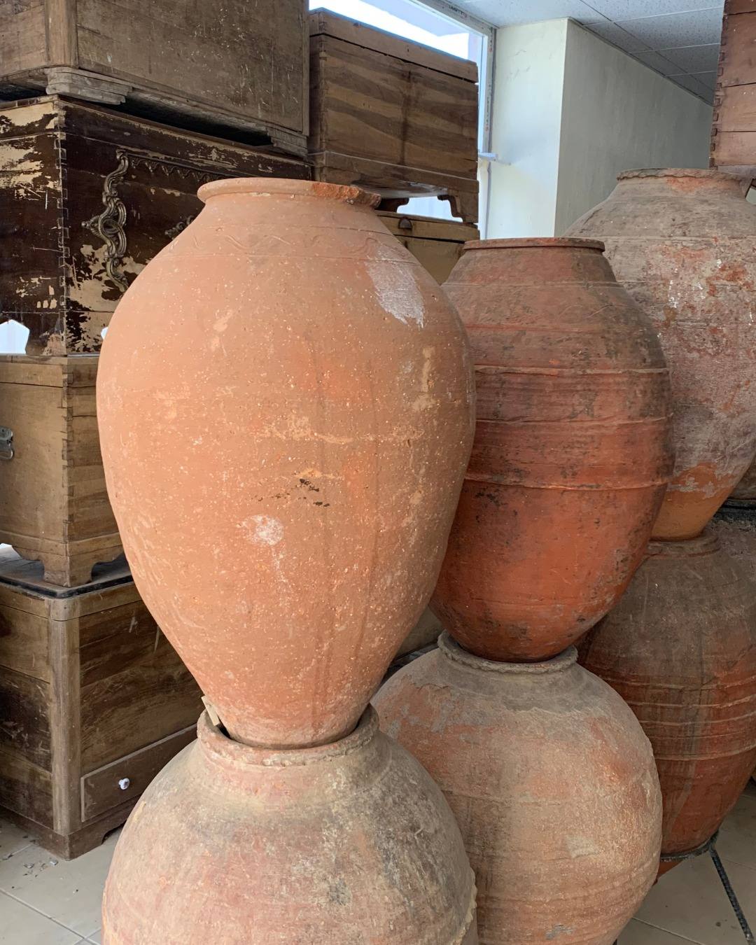 Large hand-thrown terracotta olive jars stacked in the depot
