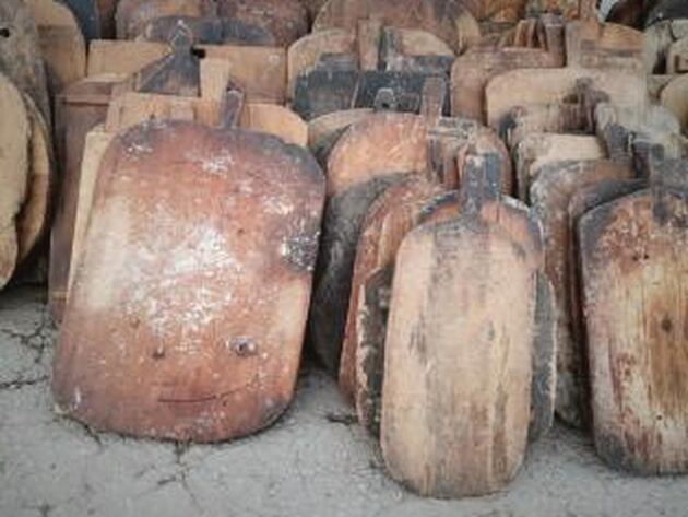 Yassiıağaç Wood Block — upright pile of worn wooden boards with handles, leaning together