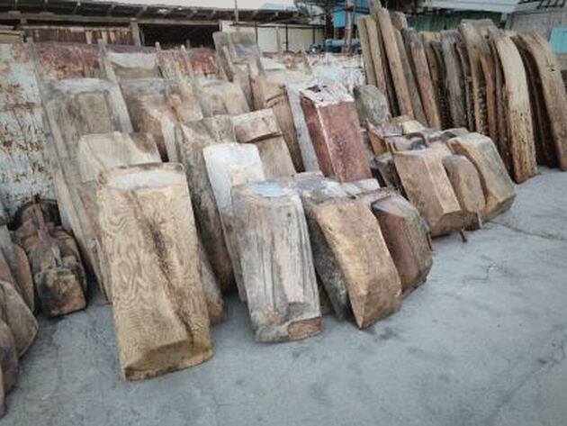 Wooden Trough, Square — reclaimed wooden blocks and slabs standing upright on a paved yard