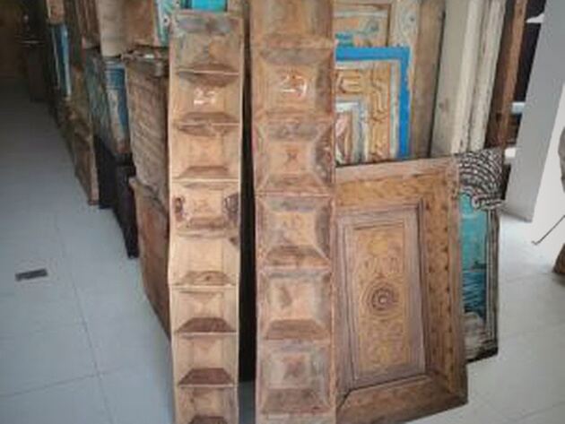 Pinyet Wood Panel — tall carved wooden panels and a studded door leaning against a wall