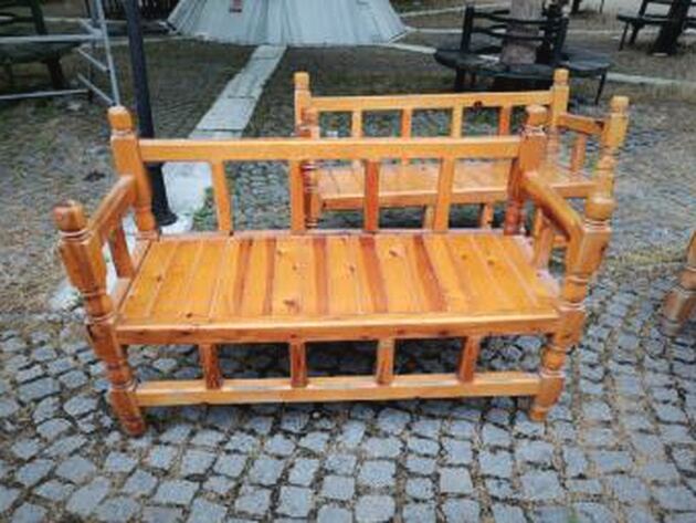 Wooden Garden Bench — honey-coloured pine bench with turned posts on cobblestones