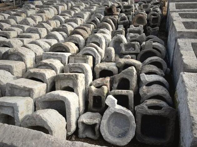 Stone Dibek Mortar — densely arranged grey carved stone mortars and troughs