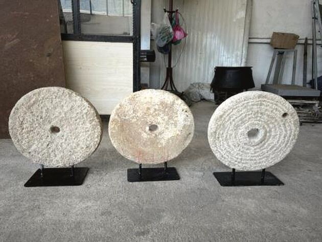 Lava Stone Wheel on Stand — three round pale stone wheels on black metal stands