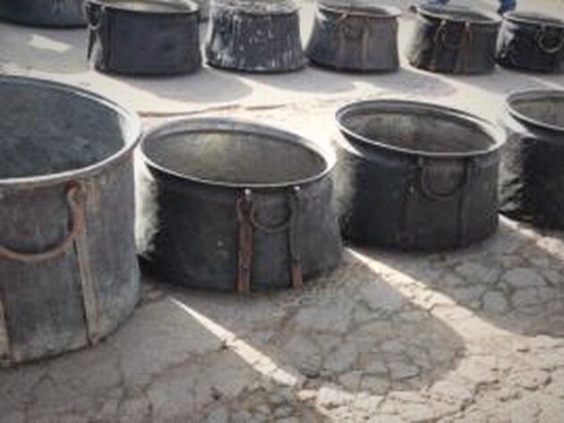 Copper Boiler — round dark copper boilers with iron handles on cracked ground