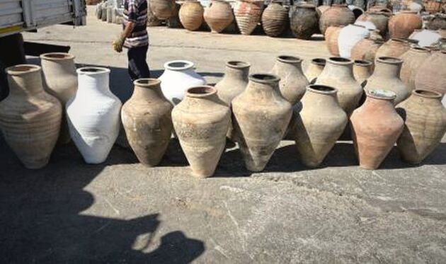 Avanos Pottery Jar — row of tall unglazed pale amphorae, one white, in an outdoor yard